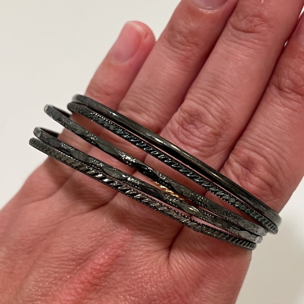 Black metal bracelet stack with different designs.